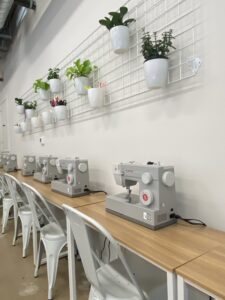 Sewing machines lined up along a wall of desks