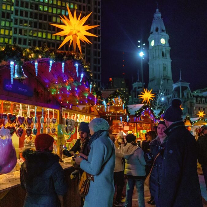 A glowing star hangs above vendor huts in Center City Philadelphia's outdoor holiday market, Christmas Village.