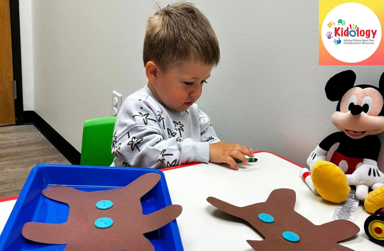 Male toddler doing art at a preschool table.