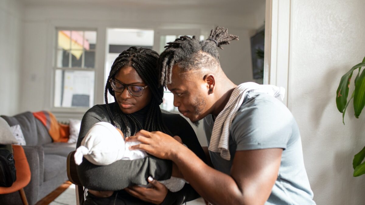 Parents snuggling a newborn baby.