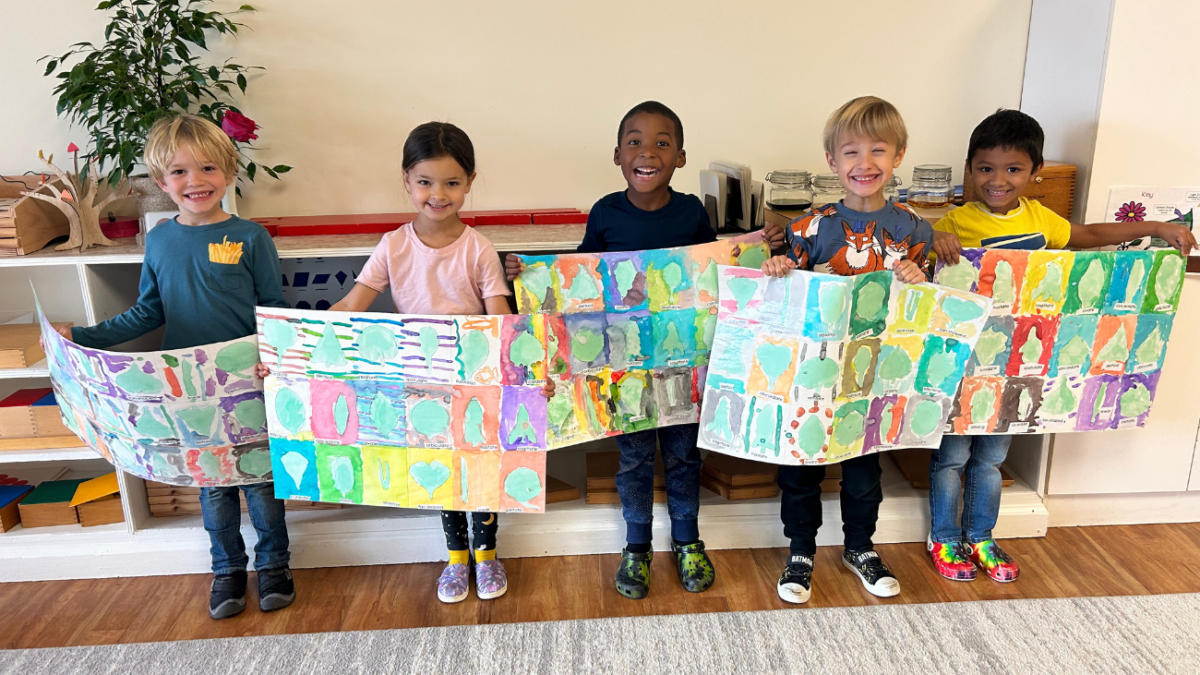 Young students standing in a row to show off their painting projects.