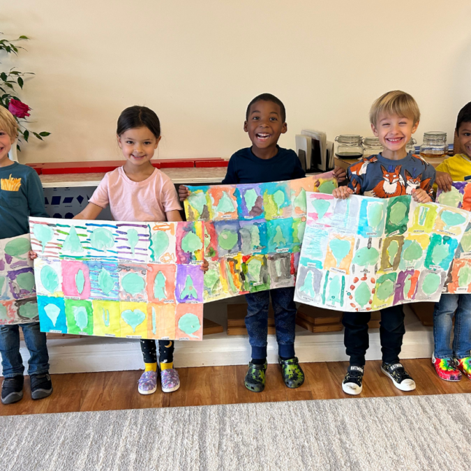 Young students standing in a row to show off their painting projects.