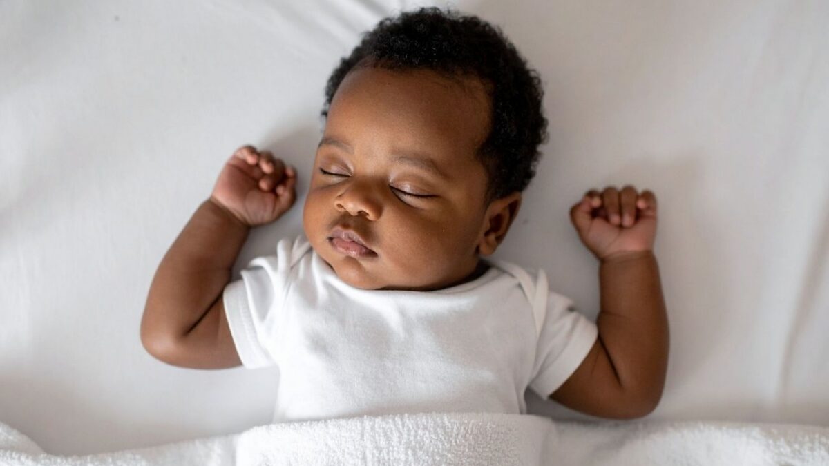 A baby sleeping in a white bed.
