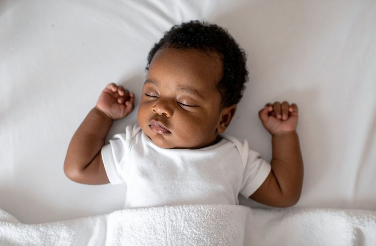 A baby sleeping in a white bed.