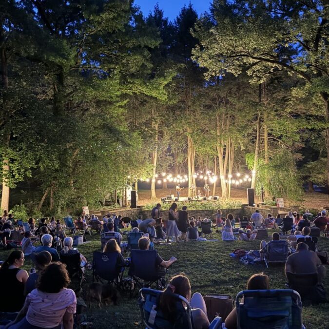 Glowing lights in the trees at twilight during a Pastorius Park Summer Concert performance.