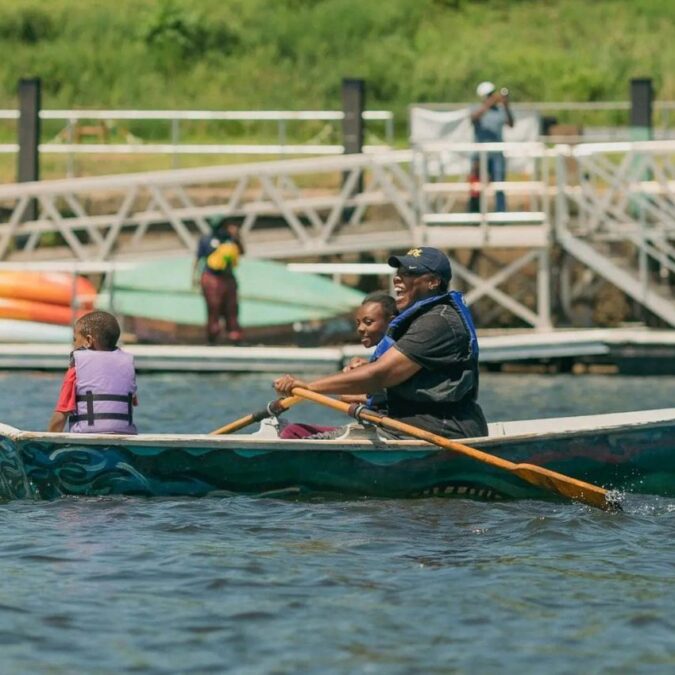 A dad and two children row a boat on Philadelphia’s Schuylkill River as part of Bartram’s Garden free summer boating.