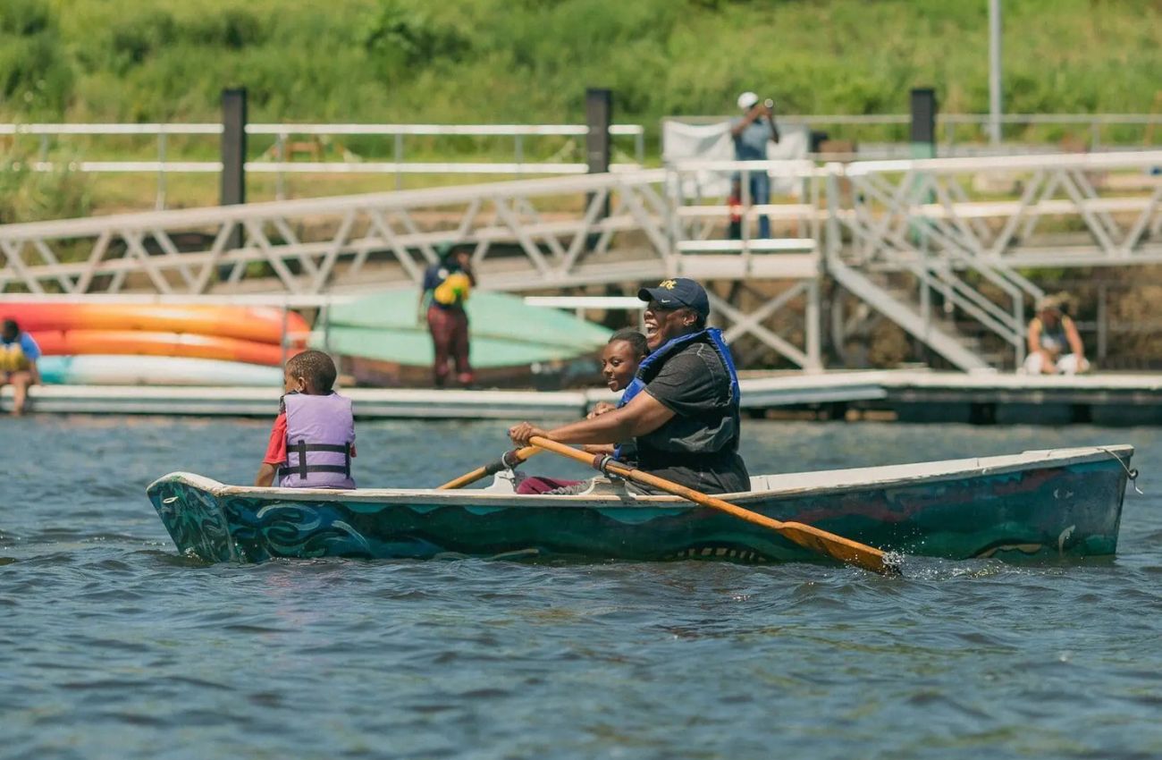 A dad and two children row a boat on Philadelphia’s Schuylkill River as part of Bartram’s Garden free summer boating.