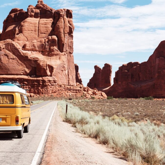 A yellow family van drives an empty road out west from the Family Road Trip Trivia Podcast.