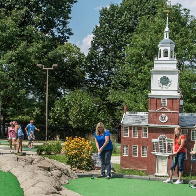 A family plays mini golf on a course with replicas of famous landmarks at Franklin Square in Philadelphia.