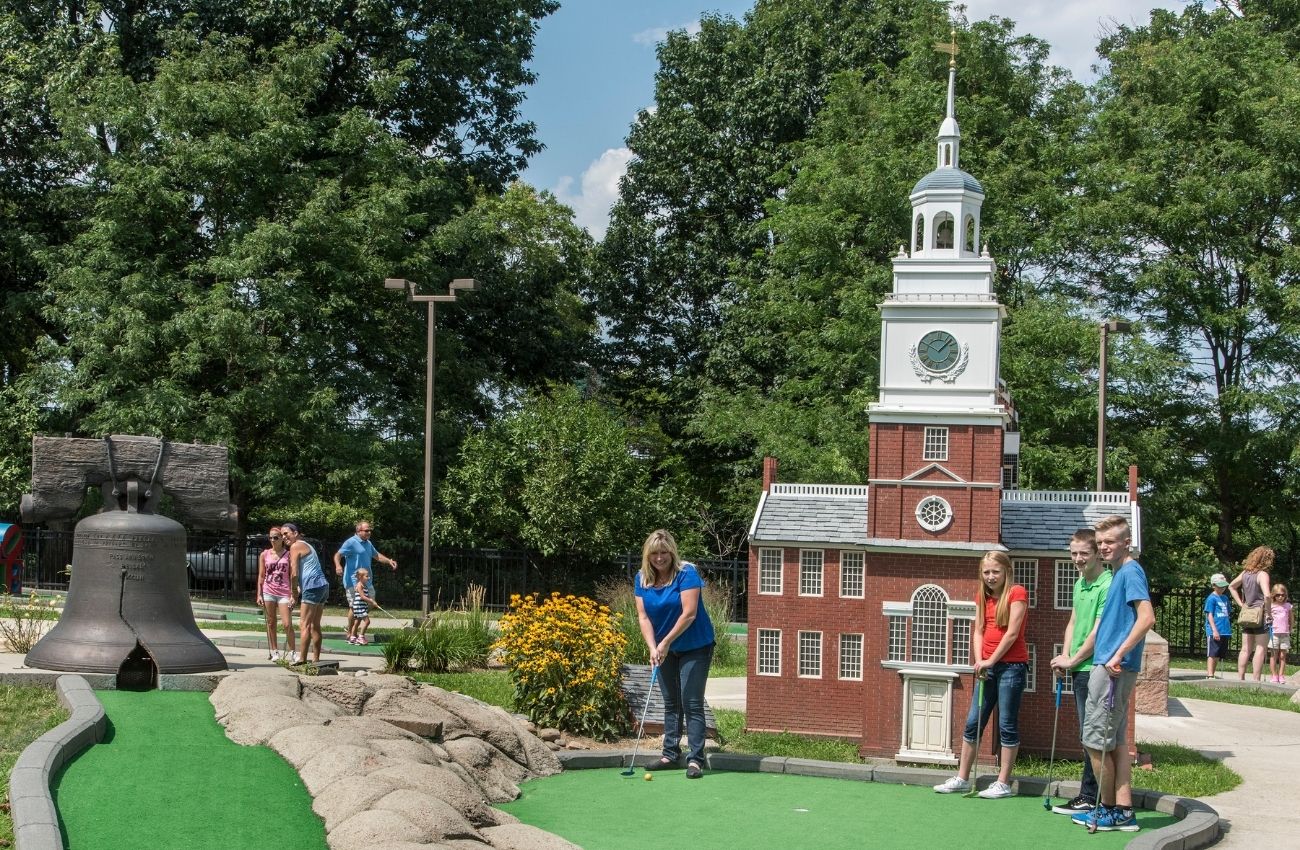 A family plays mini golf on a course with replicas of famous landmarks at Franklin Square in Philadelphia.