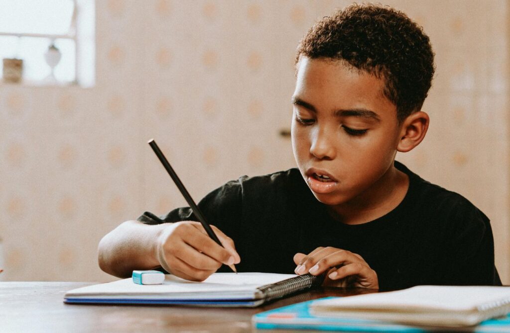 A young boy does homework at a table.