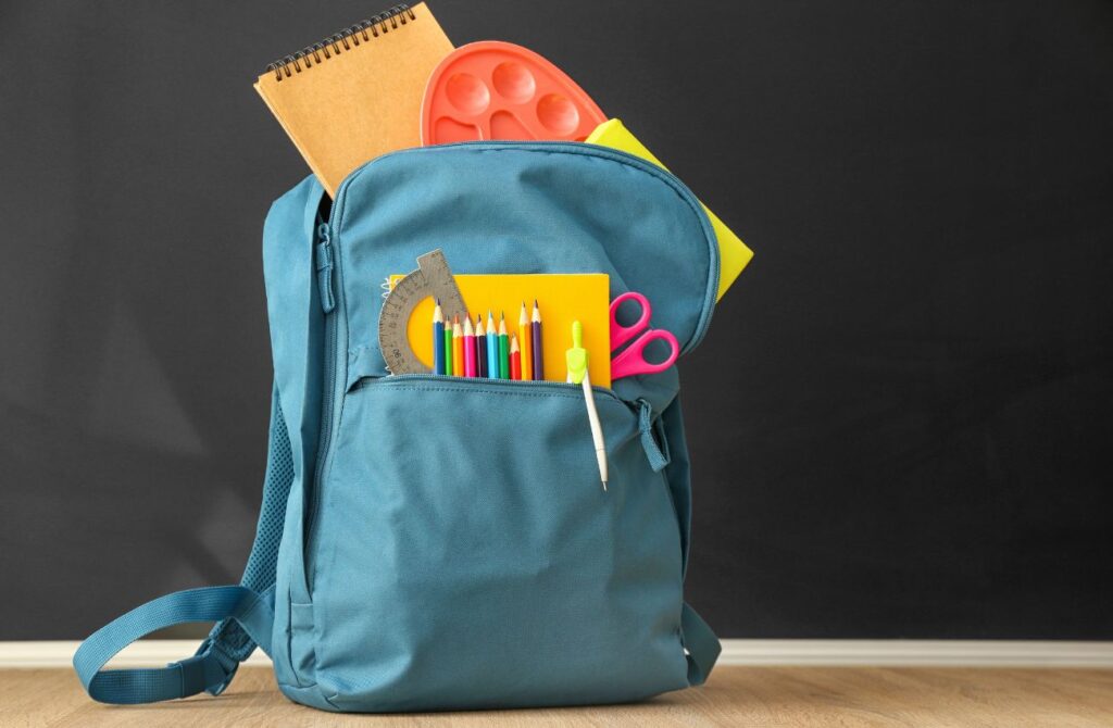 An aqua-blue backpack filled with back-to-school supplies.