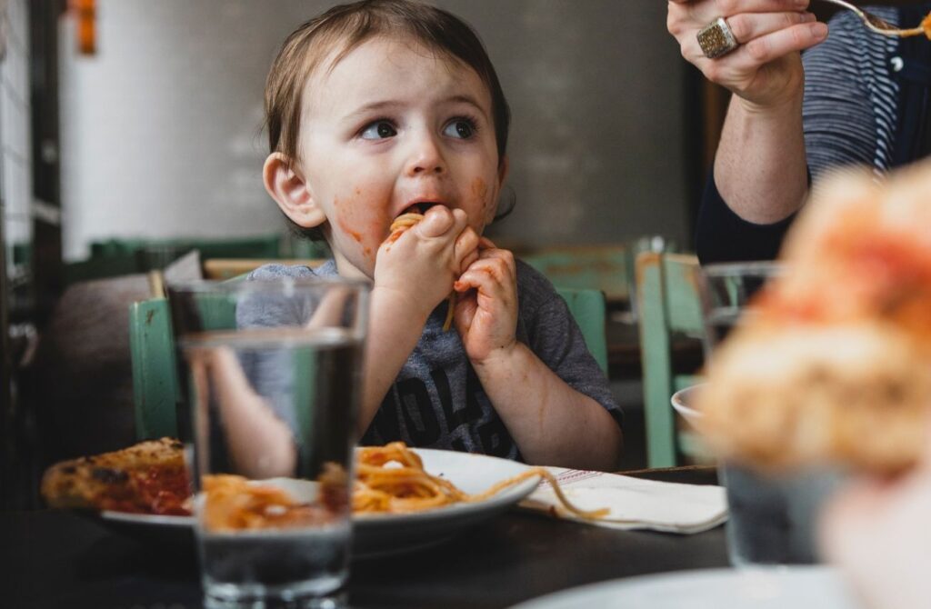 A toddler eats spaghetti with her hands at Pizzeria Stella in Philadelphia.