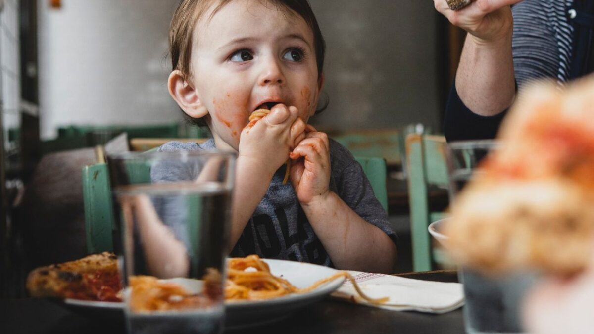 A toddler eats spaghetti with her hands at Pizzeria Stella in Philadelphia.