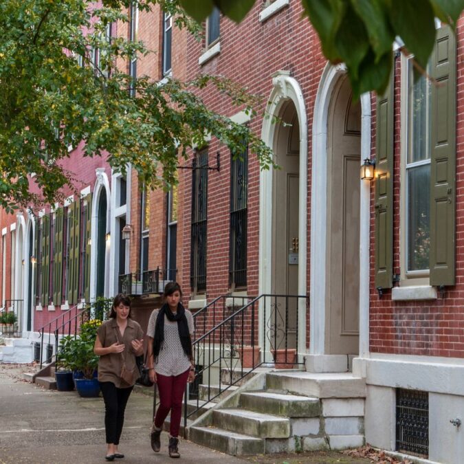 Two women stroll the tree-lined stretch of Spring Garden street in the Fairmount neighborhood in Philadelphia.