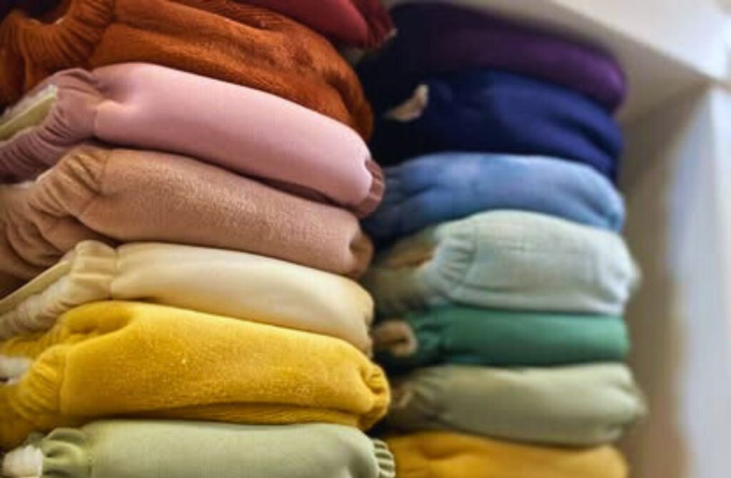 A stack of colorful cloth diaper covers on the shelf at Nesting House.