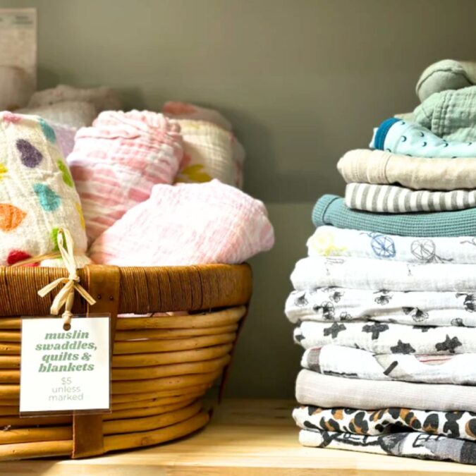 A shelf at Nesting House holds fabric swaddlers for babies.
