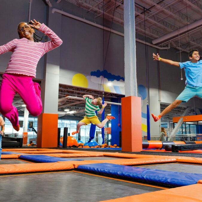 Four smiling kids jump on trampolines at Sky Zone in Philadelphia.
