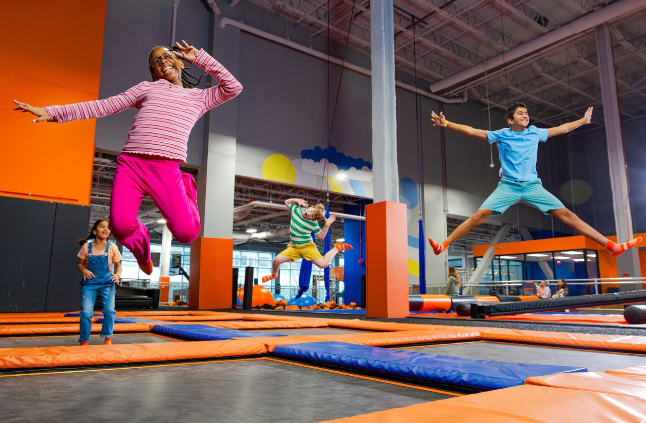 Four smiling kids jump on trampolines at Sky Zone in Philadelphia.