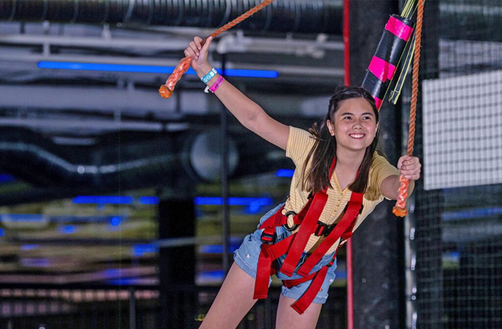 A teen girl ziplines at Urban Air.