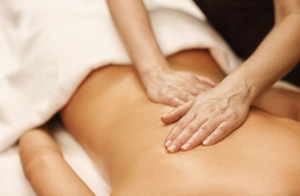 A massage therapist places hands on a client's back at Body Restoration Spa in Philly. 