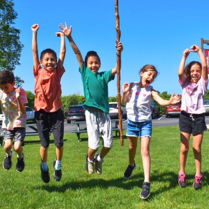 Campers jumping for joy at the entrance to ESF Camp