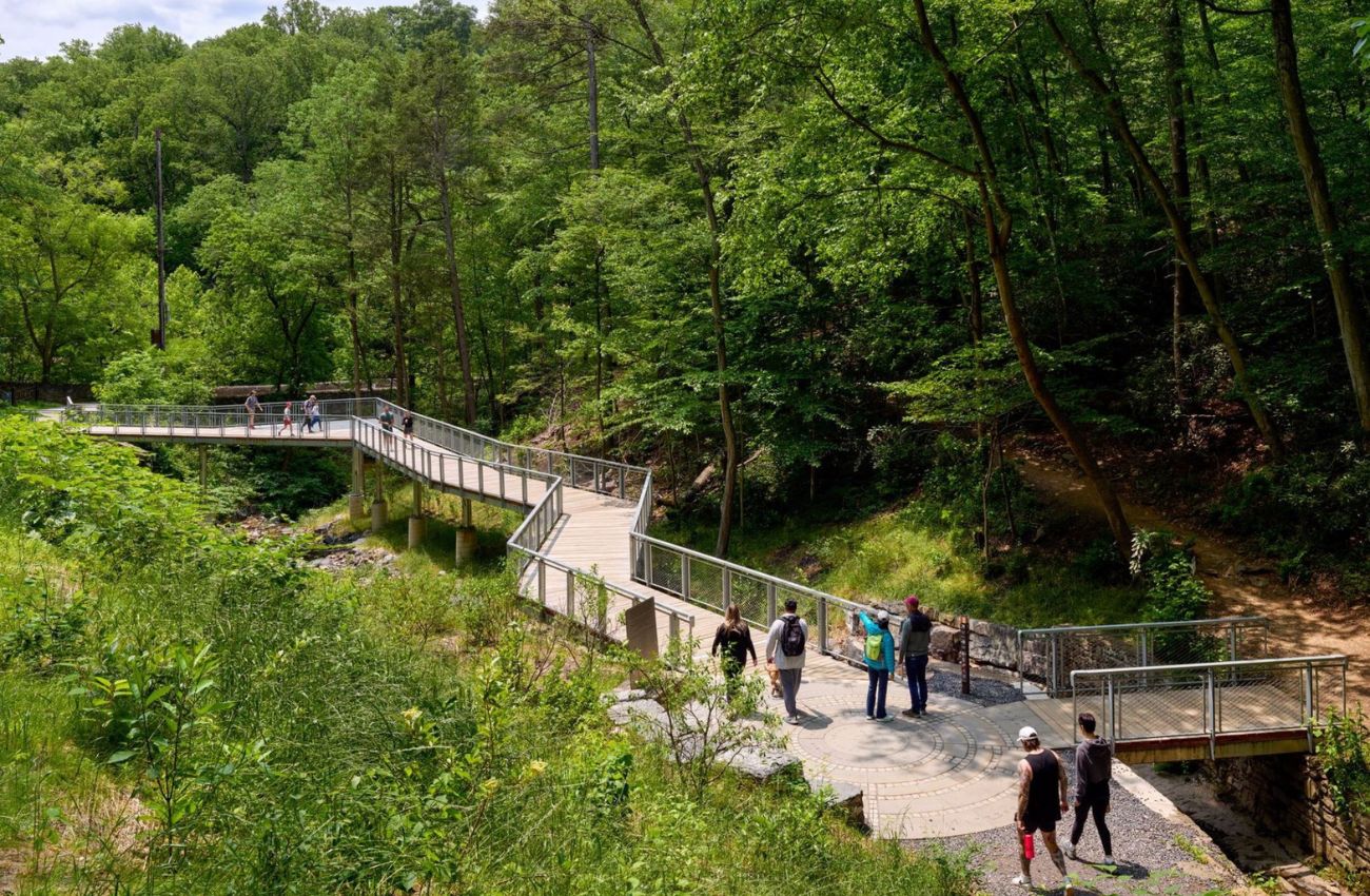 Walkers on the Lida Way pedestrian bridge surrounded by trees in Wissahickon Valley Park in Philadelphia.
