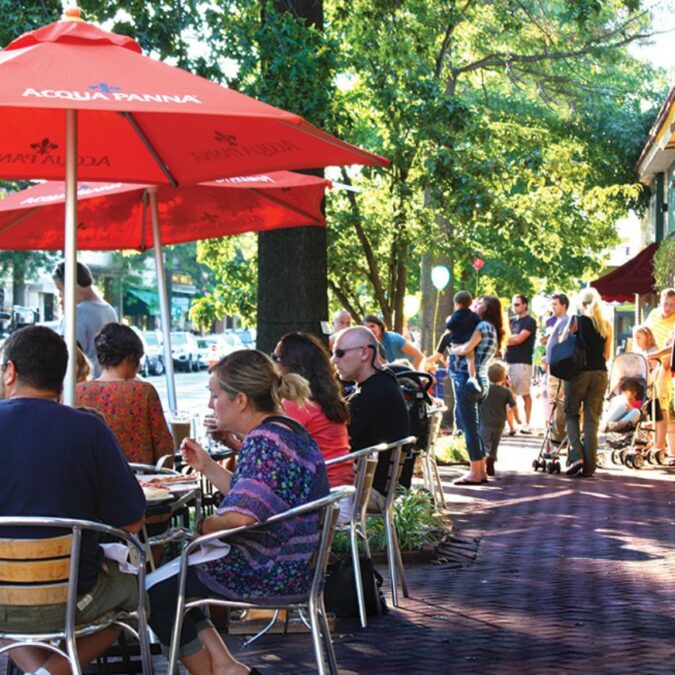 Diners outside on the sidewalk sit under red umbrellas at a busy restaurant on Haddon Avenue in downtown Collingswood.
