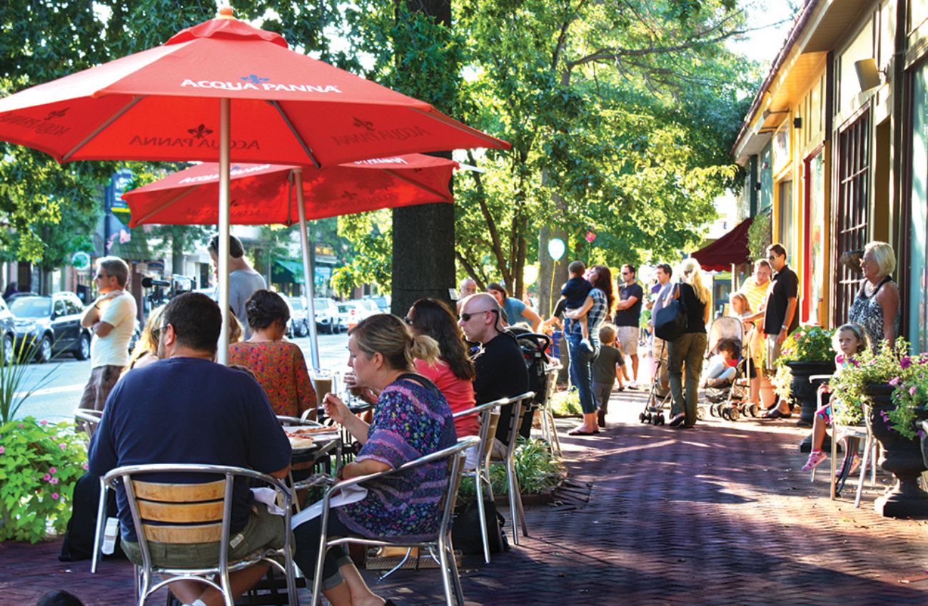 Diners outside on the sidewalk sit under red umbrellas at a busy restaurant on Haddon Avenue in downtown Collingswood.