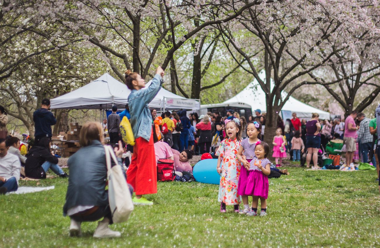 A woman takes a photo of three little girls at the Philadelphia Cherry Blossom Festival.