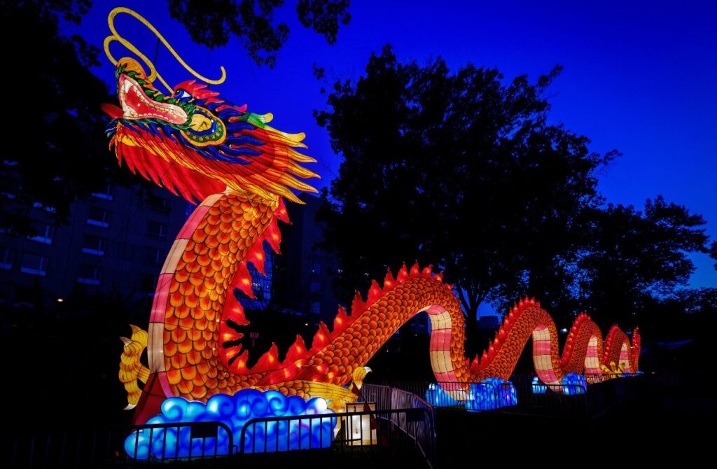 A glowing red dragon stretches across part of Franklin Square Park in Philadelphia at twilight. 
